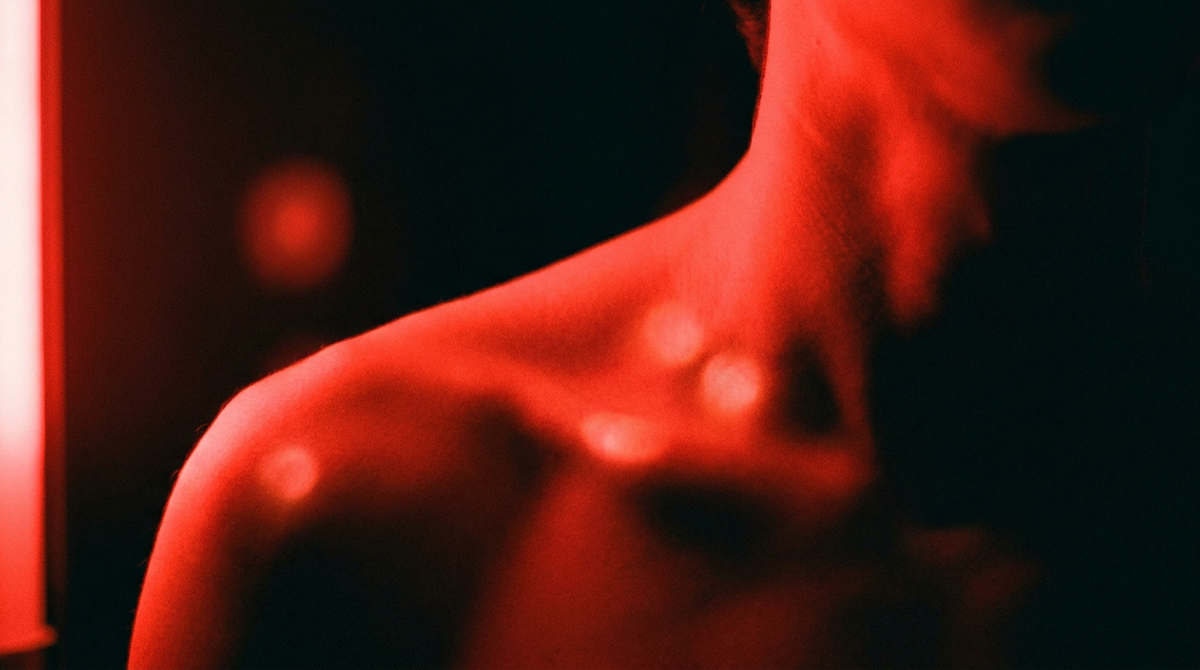 Schouder en nek in fel rood licht tegen een donkere achtergrond