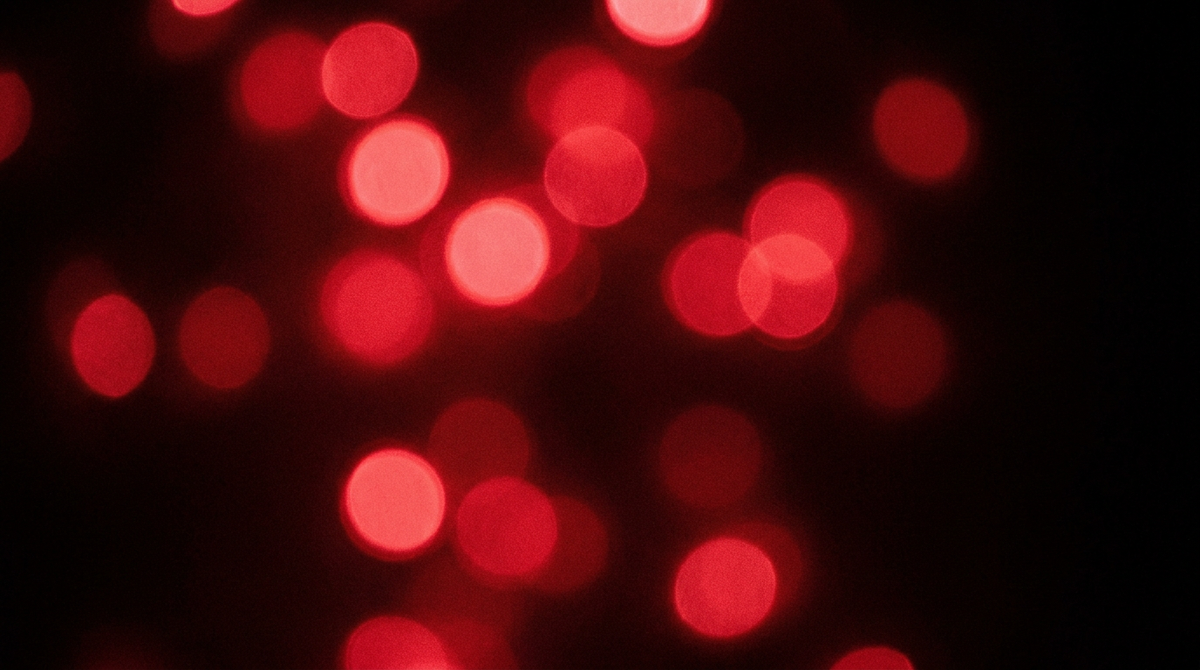 Rode lichtpunten volledig buiten focus als abstracte bokeh tegen zwart