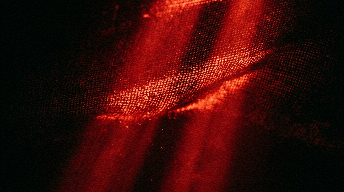 Rode lichtstralen die door de weving van textiel schijnen