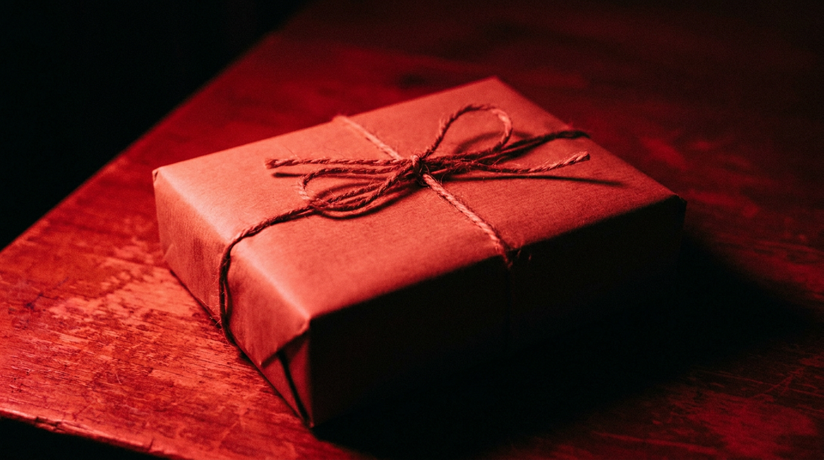 Cadeau in eenvoudig kraftpapier met een touwtje, in diep rood licht