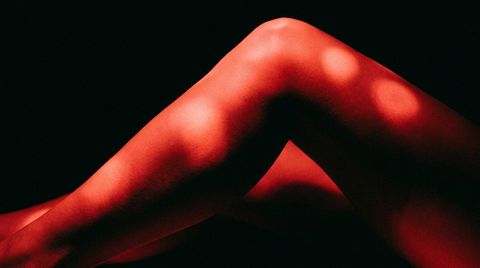 Kuit en knie in close-up onder fel rood licht tegen een donkere achtergrond