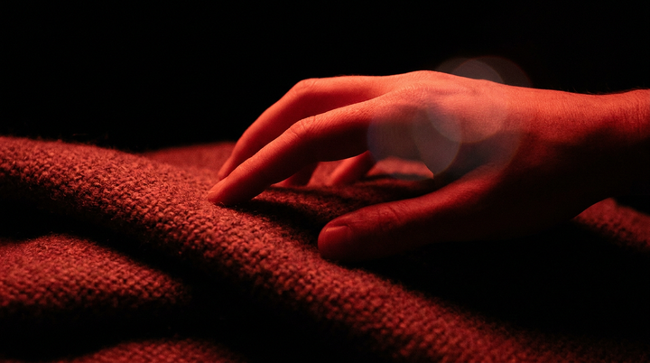 Hand die de stof van een opgevouwen deken voelt in rood licht