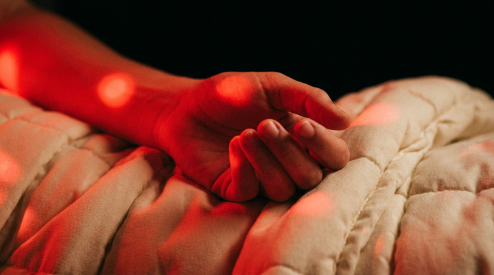 Hand op een dikke opgevouwen deken die warm oplicht onder rood licht