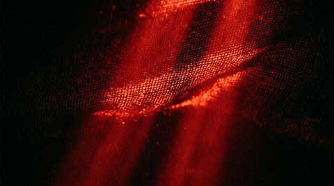 Rode lichtstralen die door de weving van textiel schijnen